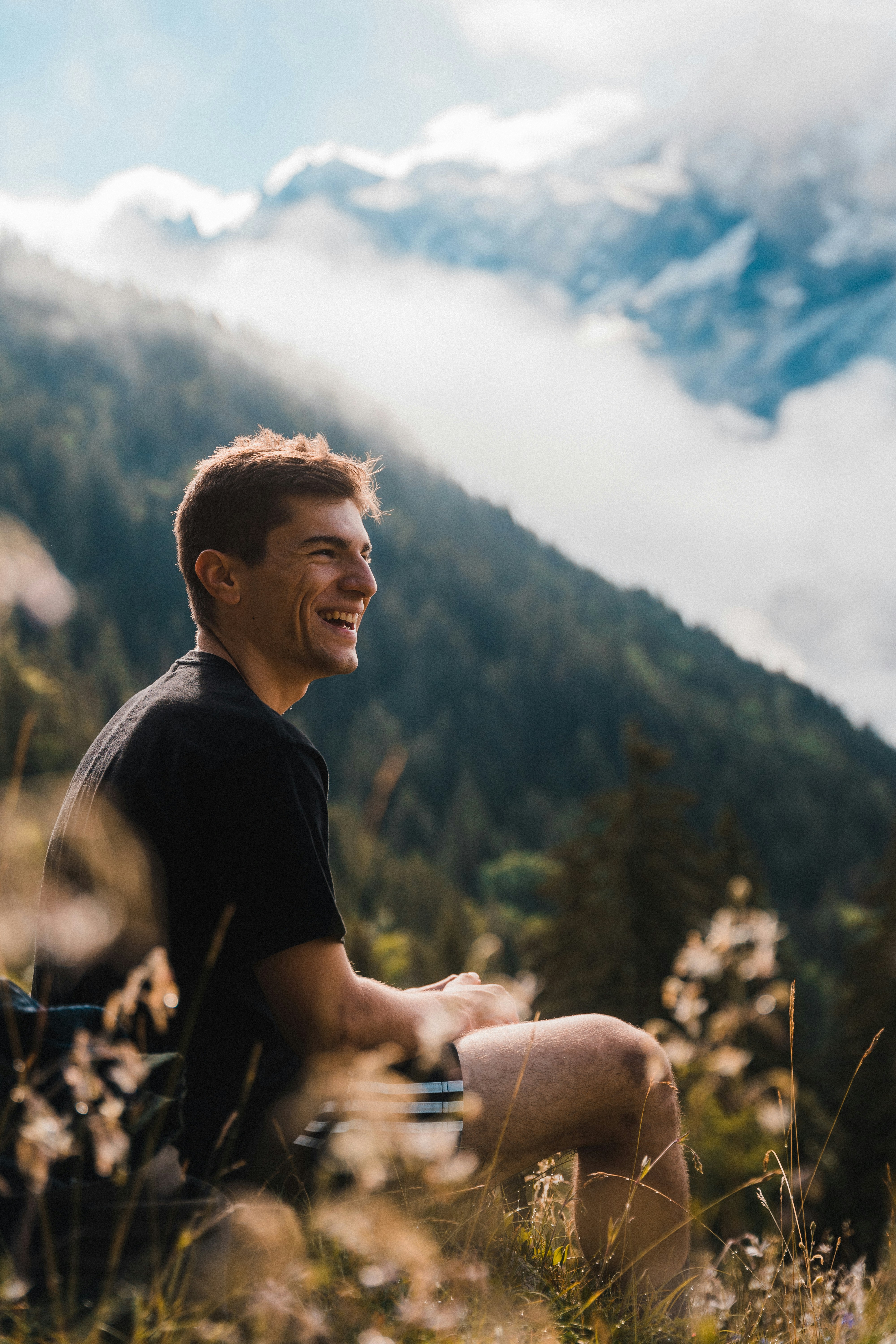 Smiling person outdoors with mountains in soft light